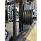 Black steel power rack with stacked weight plates loaded on right side, gym equipment in background