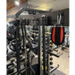 Black multi-functional power rack with integrated cable machine, red and black heavy bag, and weight storage in gym setting