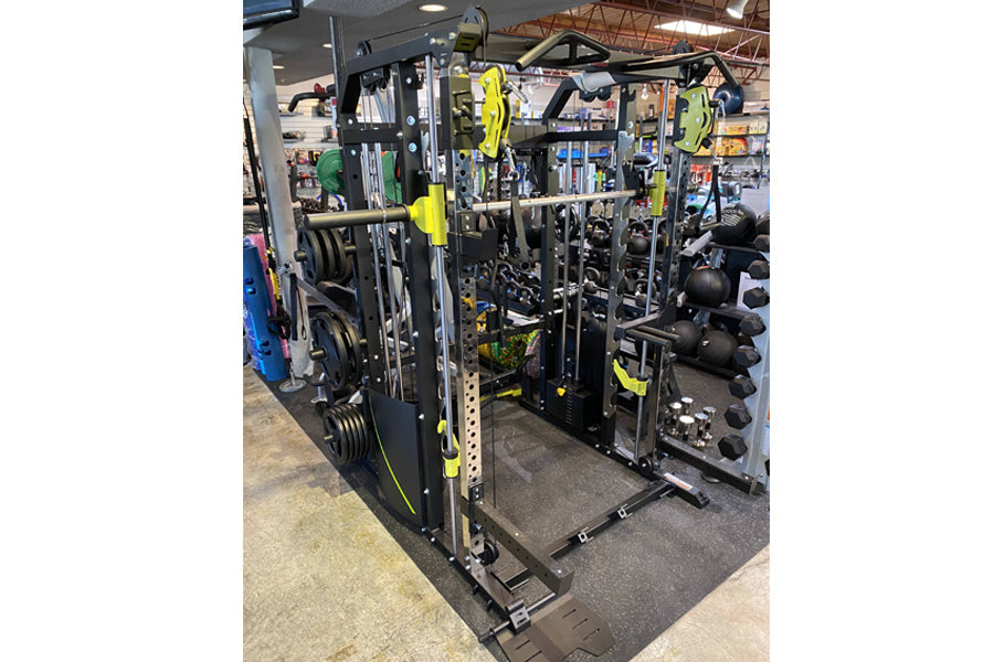 Black and yellow multi-station home gym with integrated smith machine, cable crossover, and functional trainer displayed on w