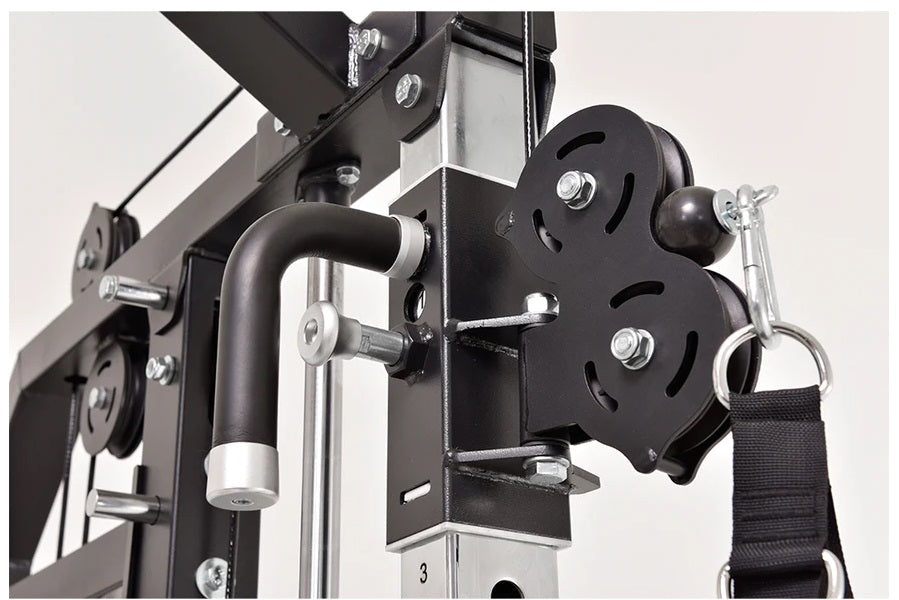Black and silver home gym cable pulley system with weight plates, handle grips, and metal frame structure on white background
