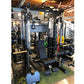 Black and silver multi-station power rack with integrated cable machine, smith machine, and leg press attachment in gym setti