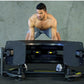 Shirtless man in blue shorts performing tire flip exercise with large black Warrior 180 tire flip equipment against concrete 