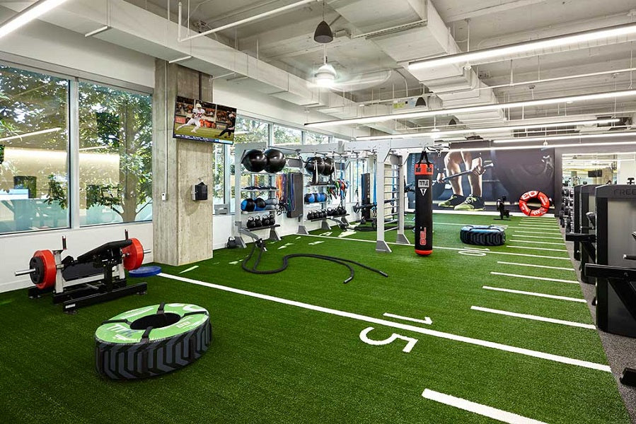 Warrior Agility Turf artificial grass flooring in modern gym space with exercise equipment and white lane markings