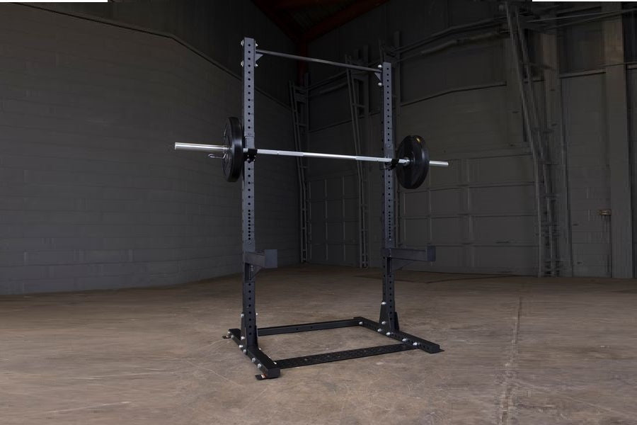 Purple and black steel half squat rack with barbell and weight plates in industrial gym setting