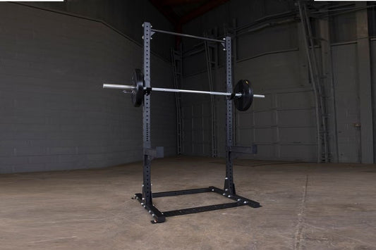 Purple and black steel half squat rack with barbell and weight plates in industrial gym setting