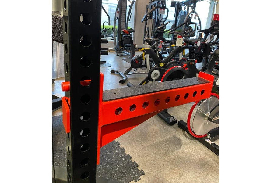 Red and black cable crossover pulley power rack with gray top platform and adjustment holes, displayed in gym setting with ex