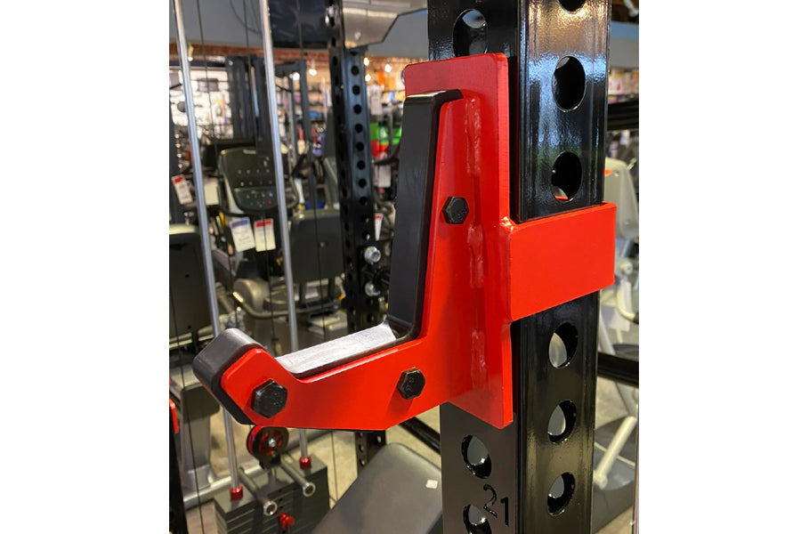 Red and black cable crossover pulley attachment mounted on power rack with adjustment holes and lever mechanism