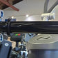 Black steel cable crossover pulley bar attached to gray power rack gym equipment with metal bolts and adjustment mechanisms