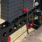 Black steel lat pulldown machine with red handles, weight plates stacked on rear post, and chrome adjustment knobs on concret