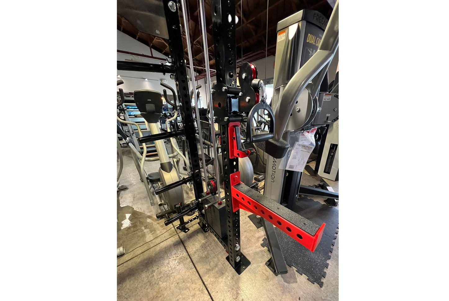 Black and red cable crossover pulley power rack with dual lat pulldown stations in gym showroom setting