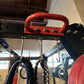 Red and black power rack with red handle bar, silver bolts, and hanging resistance bands in gym setting