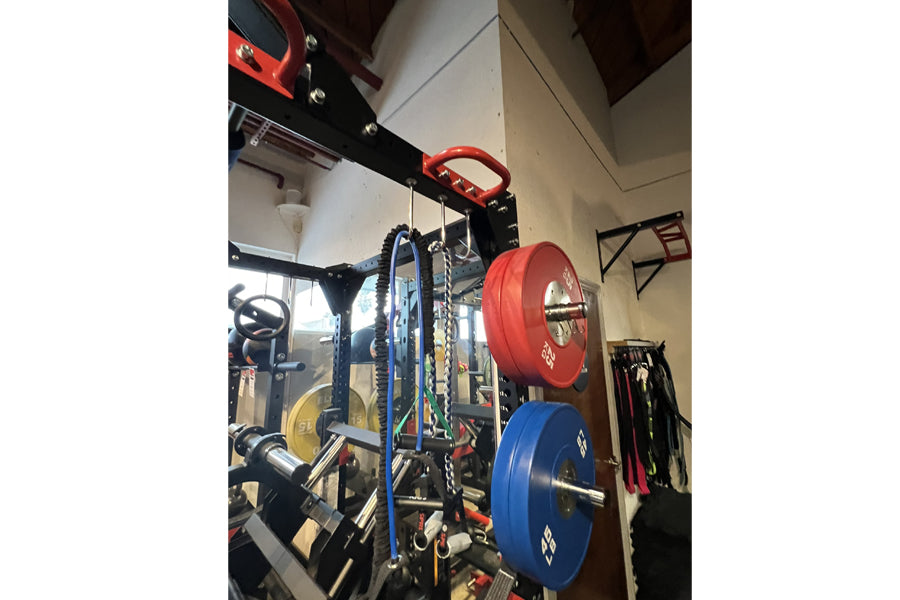 Warrior Cage/Rig Combo with red and blue weight plates, red pull-up bar, and black frame in gym setting