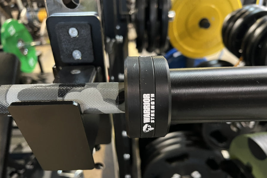 Warrior 6-bearing cerakote barbell bar with gray camo sleeve design, displayed in gym setting