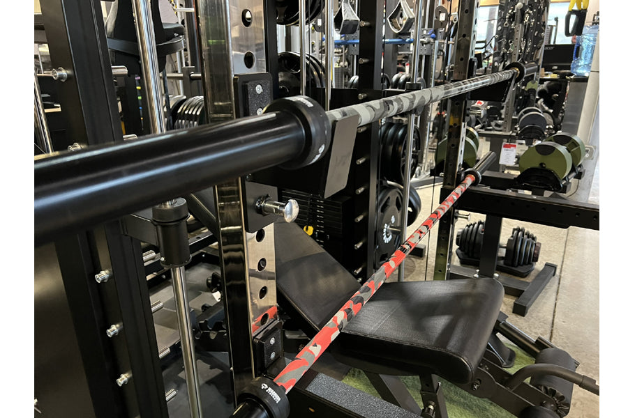 Warrior 6-bearing Cerakote barbell with red and gray camo pattern, mounted on gym equipment