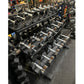 Warrior Pro-Style chrome dumbbell set arranged on black rack in gym, ranging from 5 to 50 pounds with numbered weights visibl