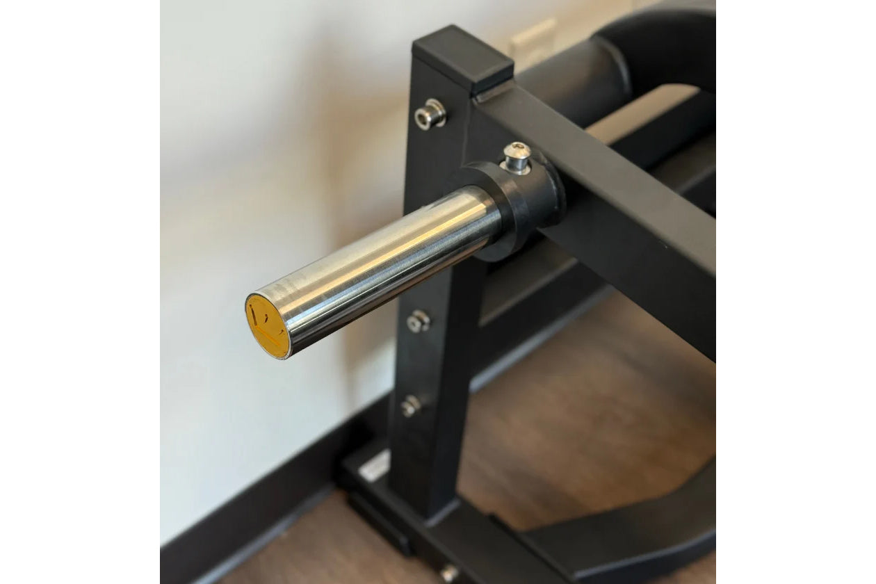 Chrome and black metal squat machine footrest with gold end cap, mounted on vertical support bracket
