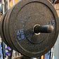 45 lb black bumper plate with blue speckles and markings on weight rack