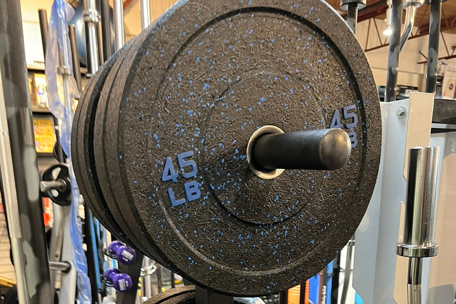 45 lb black bumper plate with blue speckles and markings on weight rack