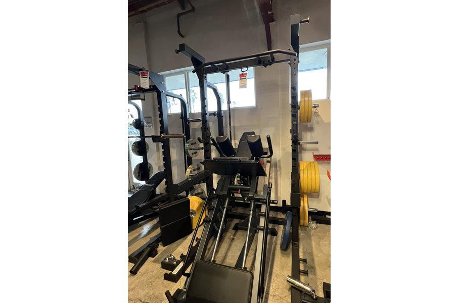 Black and yellow Warrior Deluxe Squat Rack with adjustable barbell holders and safety arms displayed in gym setting