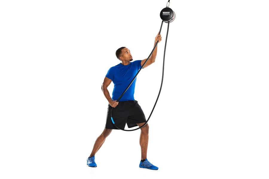 Man wearing blue t-shirt and black shorts using black rope pulley trainer system on white background