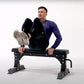 Man wearing blue long-sleeve shirt and black pants sitting on black Warrior flat bench with feet up, white background