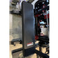 Black flat weight bench with red Warrior branding and locking wheels, shown in warehouse setting next to 3D printer
