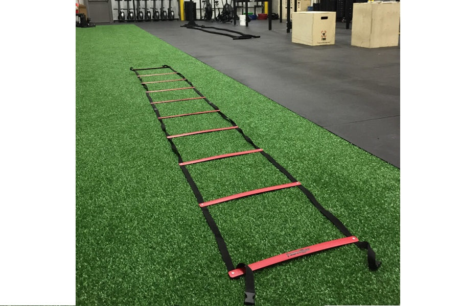 Warrior Gorilla Turf agility ladder with red rungs and black sides on green artificial turf
