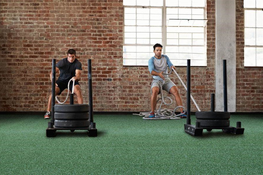 Warrior Gorilla Turf green athletic flooring in industrial gym space with two men exercising with battle ropes