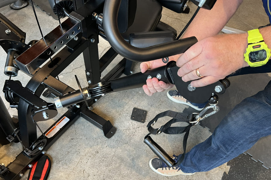 Person demonstrating leg press attachment on black Warrior HG900 home gym with foot pedal and straps