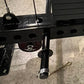 Black metal lat pulldown and low-row attachment with cable arms and adjustment holes, mounted overhead view on concrete backg
