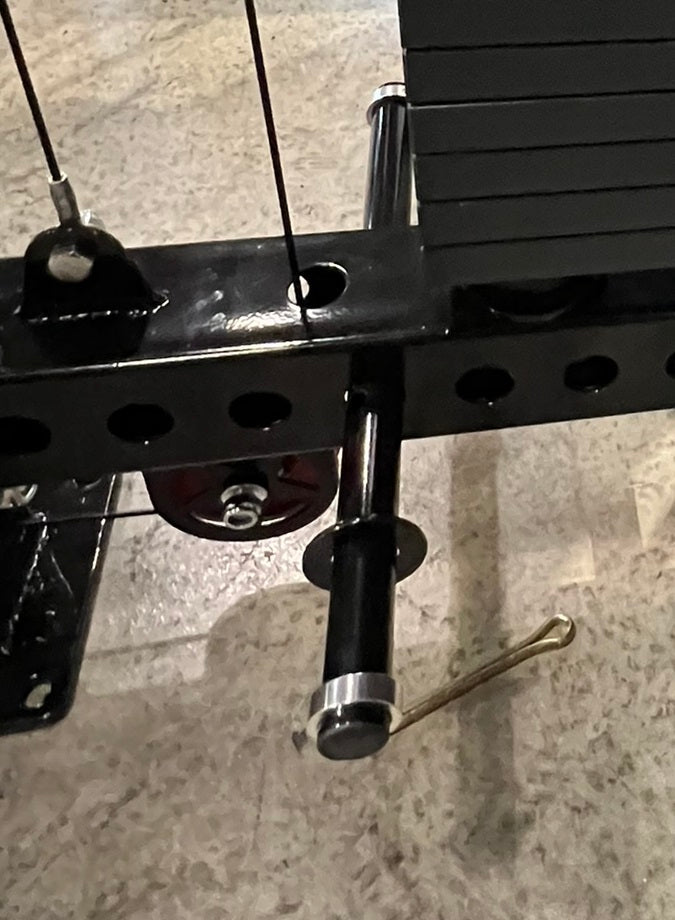 Black metal lat pulldown and low-row attachment with cable arms and adjustment holes, mounted overhead view on concrete backg