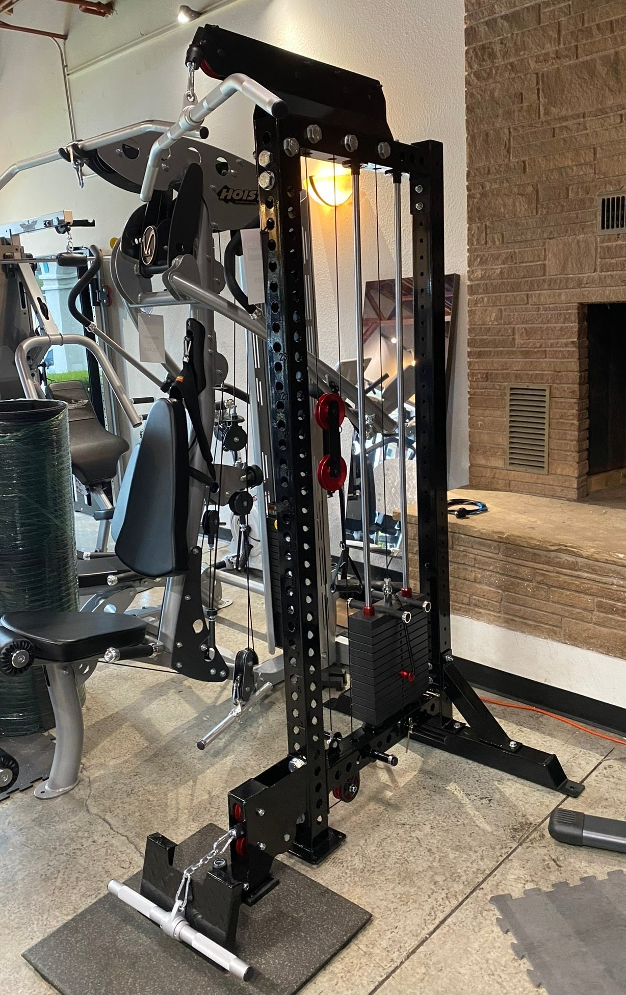 Black and silver cable machine with lat pulldown and low-row attachments in gym setting