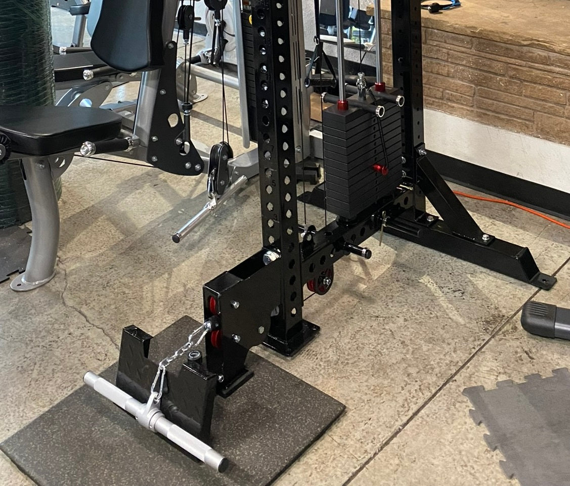 Black steel lat pulldown and low-row home gym system with weight stack and adjustable pulleys on garage floor