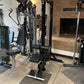 Black and silver Warrior lat pulldown and low-row home gym machine with padded seat and footplate on concrete floor in gym se