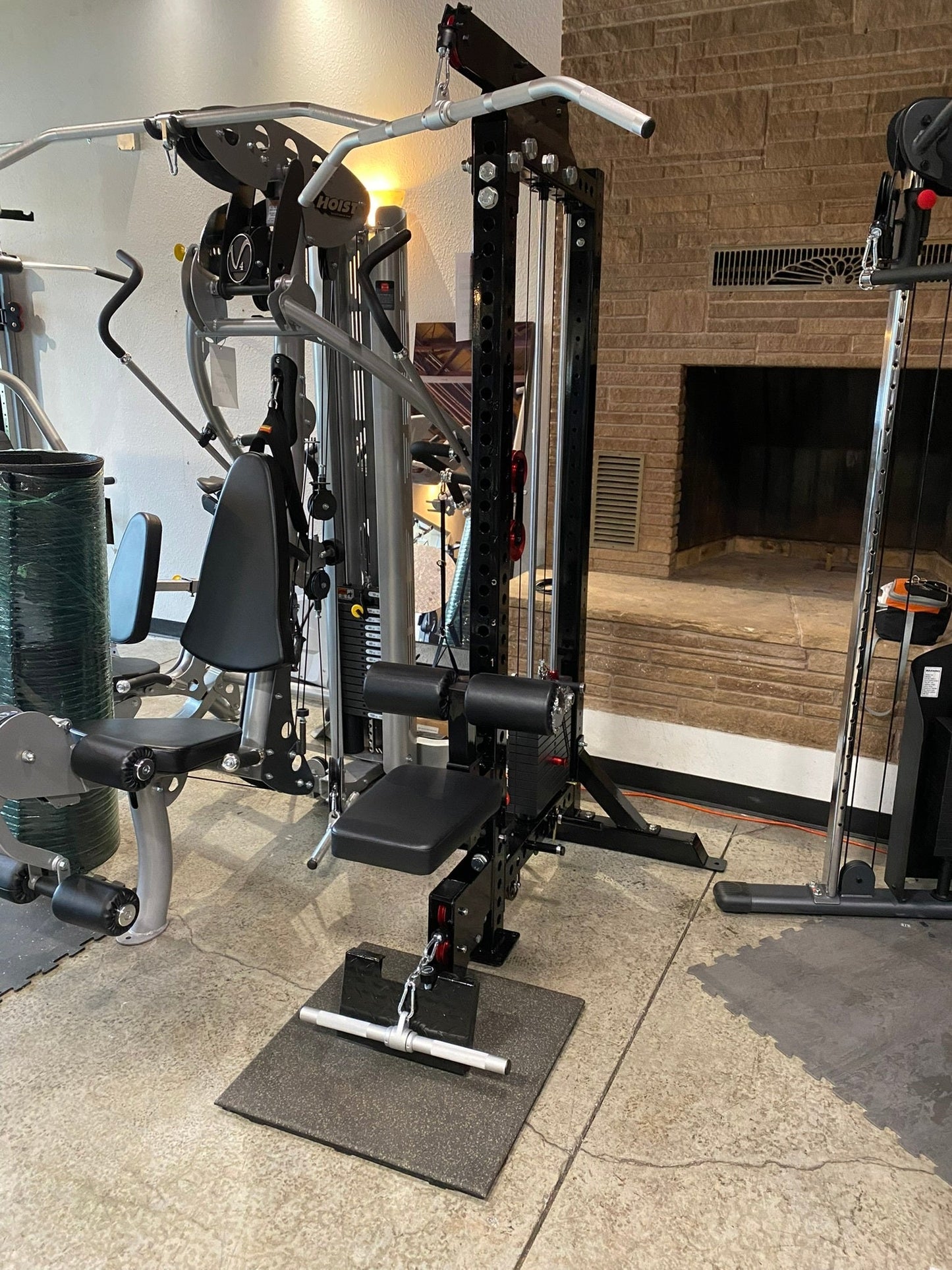 Black and silver Warrior lat pulldown and low-row home gym machine with padded seat and footplate on concrete floor in gym se