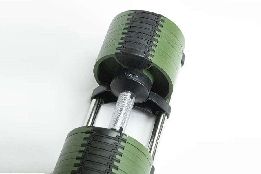Pair of green and black adjustable dumbbells with metal handle and weight adjustment mechanism, overhead view on white backgr