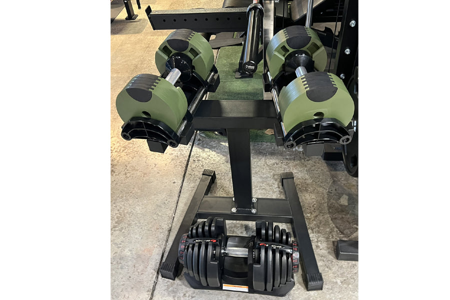 Warrior Newbells 50lb adjustable dumbbells with olive green and black design on weight rack, flat lay