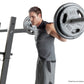 Man in black tank top performing shoulder press on black steel Olympic weight bench with loaded barbell bar on white backgrou