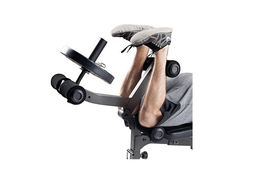 Man performing leg press exercise on black and gray multi-function weight bench with adjustable footrest and handles