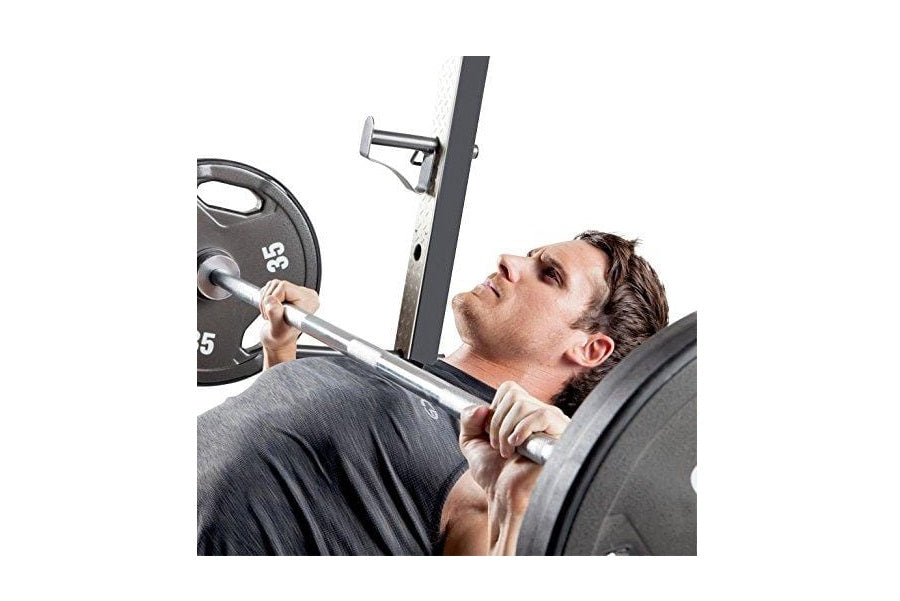 Man performing bench press exercise on black Olympic weight bench with loaded barbell and weight plates