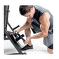 Male athlete using black and gray Olympic weight bench with adjustable seat and leg extension attachment