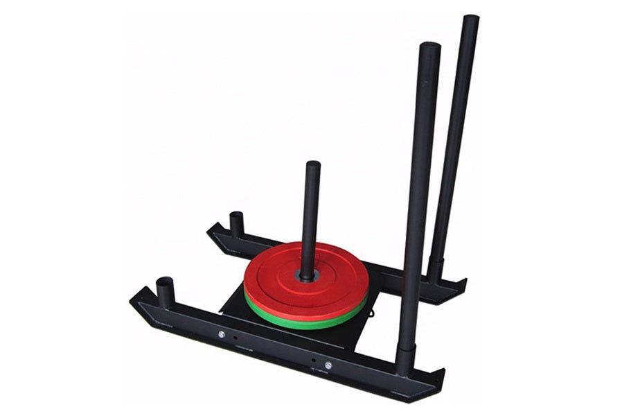 Black weight sled with red and green weight plates stacked on center post and two tall black vertical handles on white backgr