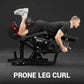 Man performing prone leg curl on black plate-loaded Warrior Signature machine, holding red dumbbells, wearing white sneakers 