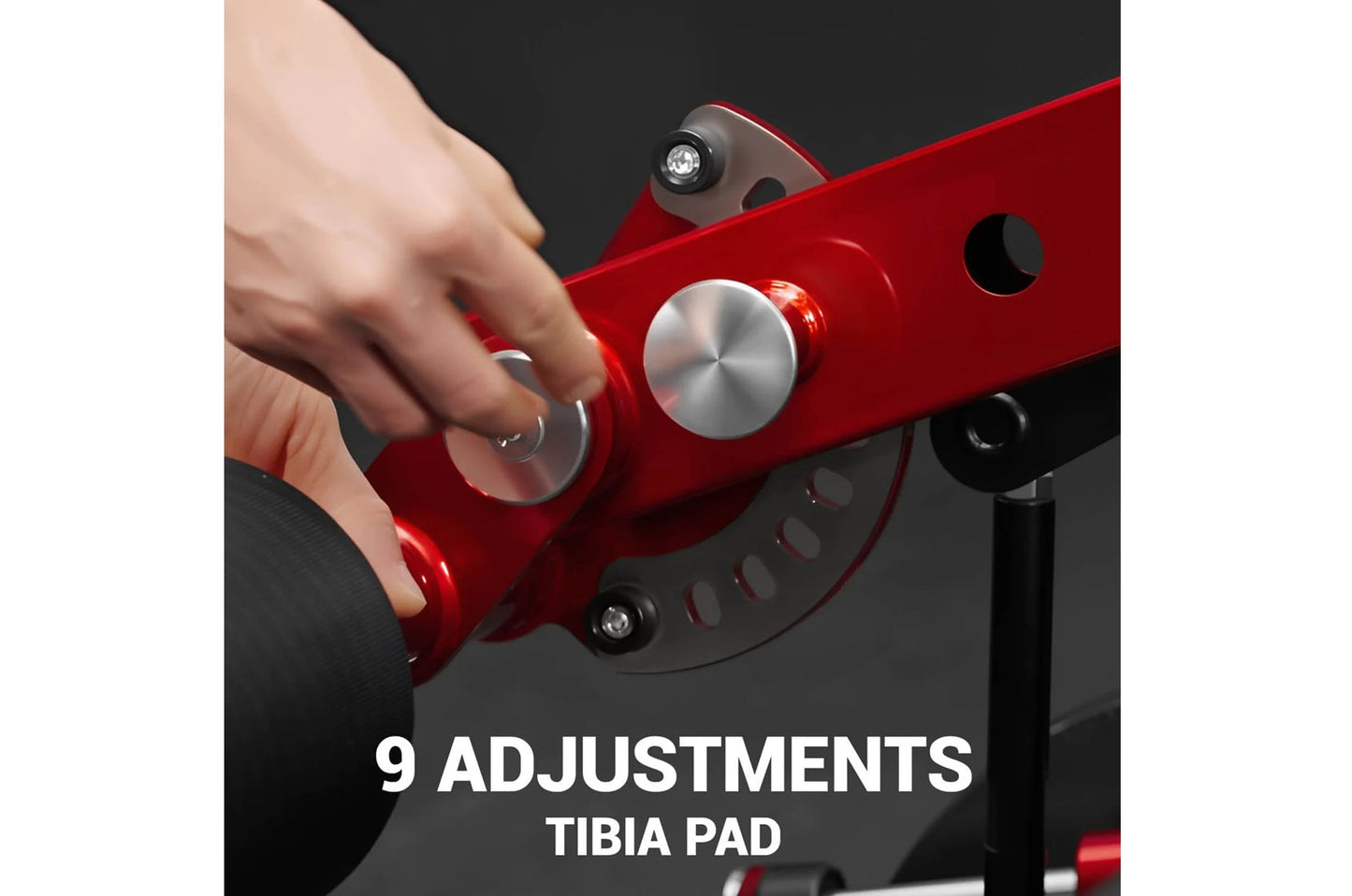 Hand adjusting red and black plate-loaded leg extension machine with silver dial control and adjustment knob