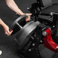 Model demonstrating black plate-loaded leg extension machine with red frame and adjustable seat, hands gripping padded lever