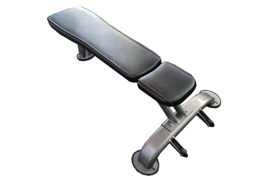 Warrior flat weight bench with black padded seat and backrest, silver metal frame with leg extension attachment, on white bac