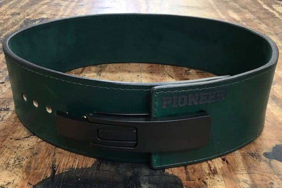 Green leather weightlifting belt with black buckle closure and metal eyelets, flat lay on wooden surface