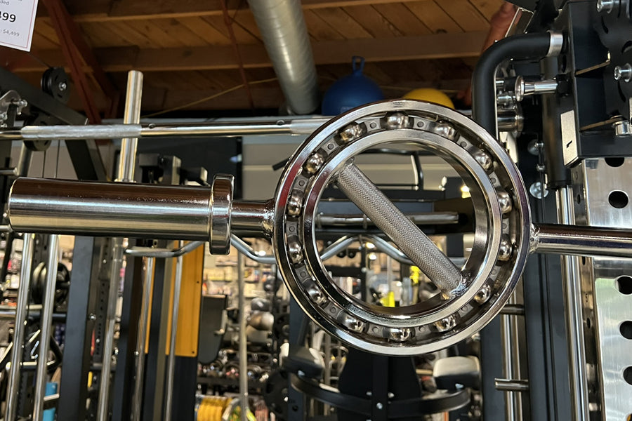 Chrome Olympic curl bar with studded collar ring and textured grip, mounted on weight rack