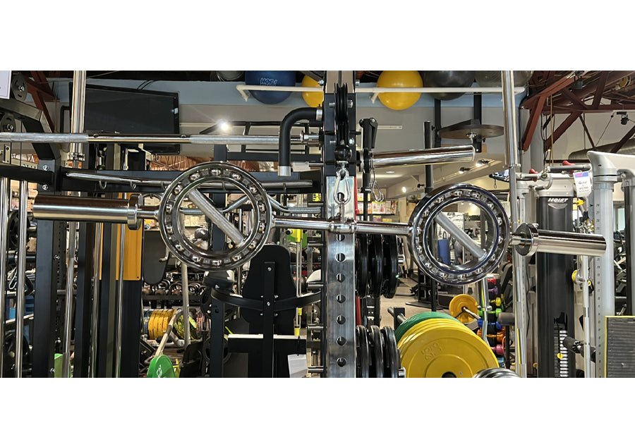 Warrior Supra EYE Olympic curl bar with black rotating sleeves and calibrated weight markings displayed in gym facility
