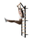 Black and natural wood wall-mounted Swedish stall bars with horizontal wooden rungs, shown in use by model wearing white spor